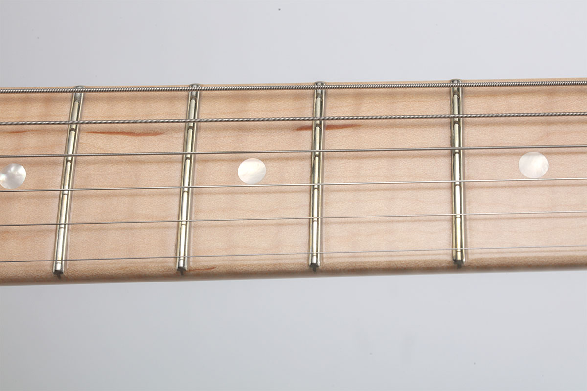 4Aグレードのフレイムが主張するメイプル・ネック。ポジション・マークのマザー・オブ・パールが華を添える。